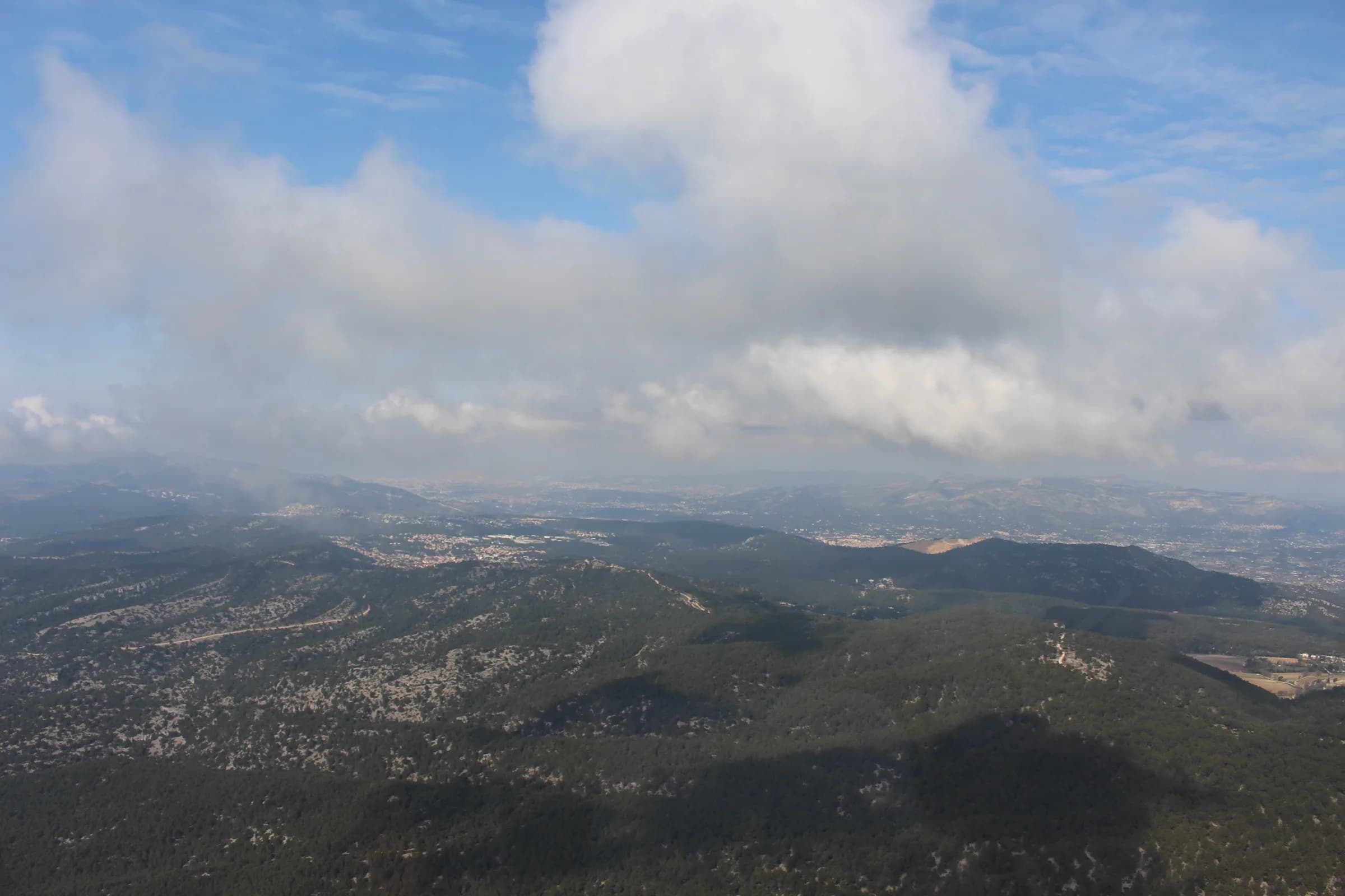 Survol des collines provençales sous un ciel voilé, vue depuis un hélicoptère
