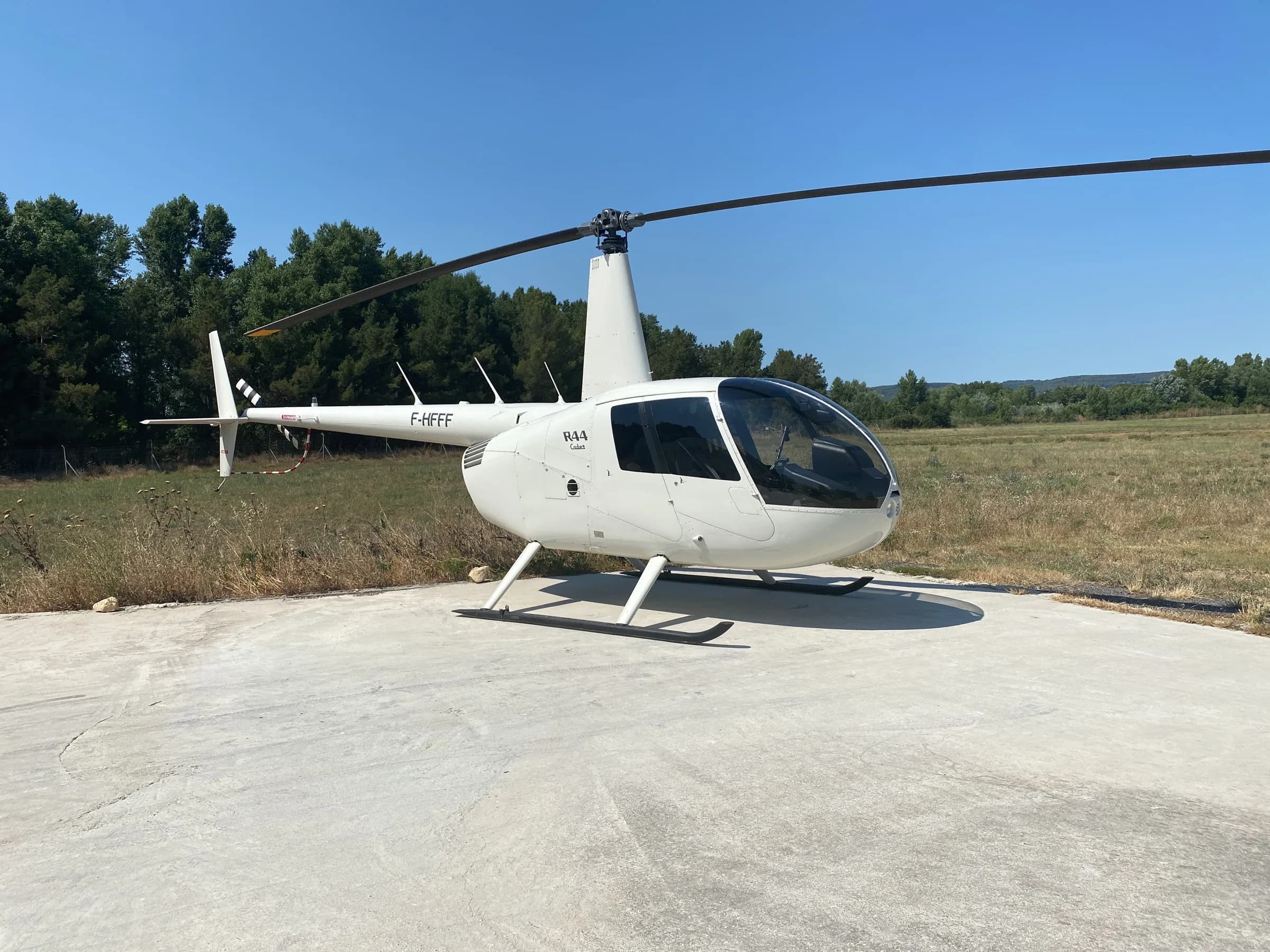 Hélicoptère Robinson R44 Cadet posé sur une aire d'envol en Provence